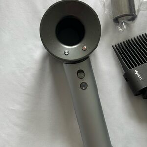 Dyson Supersonic Hair Dryer in Gray with attachments and stand.